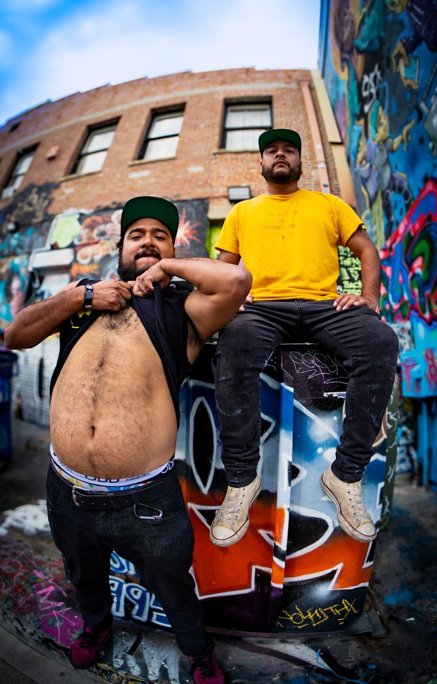 Two artists posing in a graffiti-covered alley